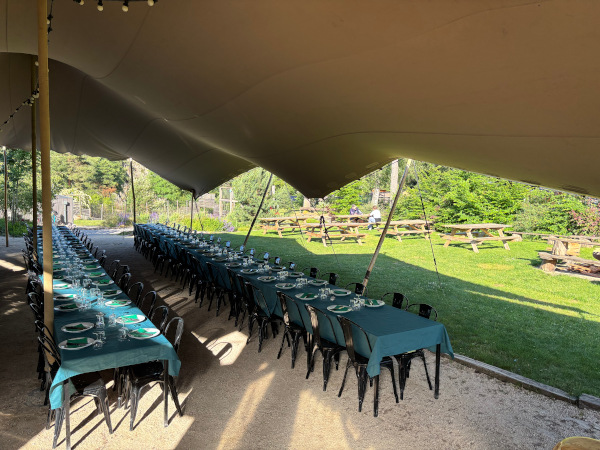 Grandes tables de réception installées sous une tente extérieure aux Murmures du Lignon en Haute-Loire.