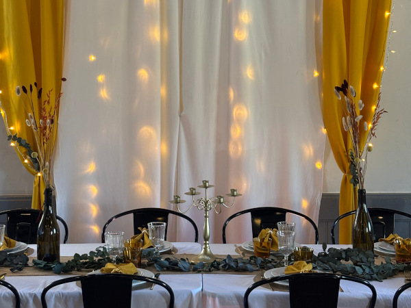 Décoration de table de réception avec bougies et compositions végétales aux Murmures du Lignon.