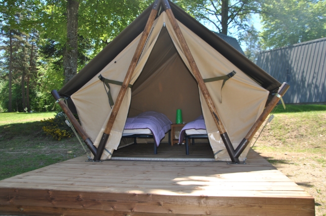 Petite tente insolite aménagée avec deux lits individuels sur une plateforme en bois à Tence.