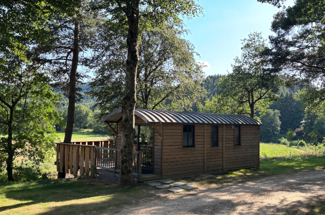 Roulotte en bois avec terrasse privative au cœur d'un domaine arboré à Tence en Haute-Loire.