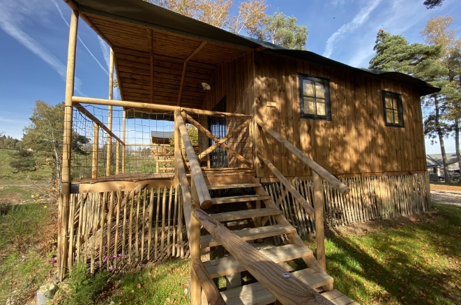 Tente lodge avec terrasse couverte dans un environnement boisé aux Murmures du Lignon en Haute-Loire.