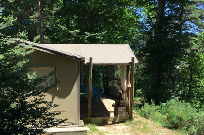 Tente lodge avec terrasse couverte dans un environnement boisé aux Murmures du Lignon en Haute-Loire.