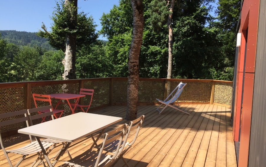 Terrasse en bois avec salon de jardin et transats dans un hébergement nature aux Murmures du Lignon à Tence.